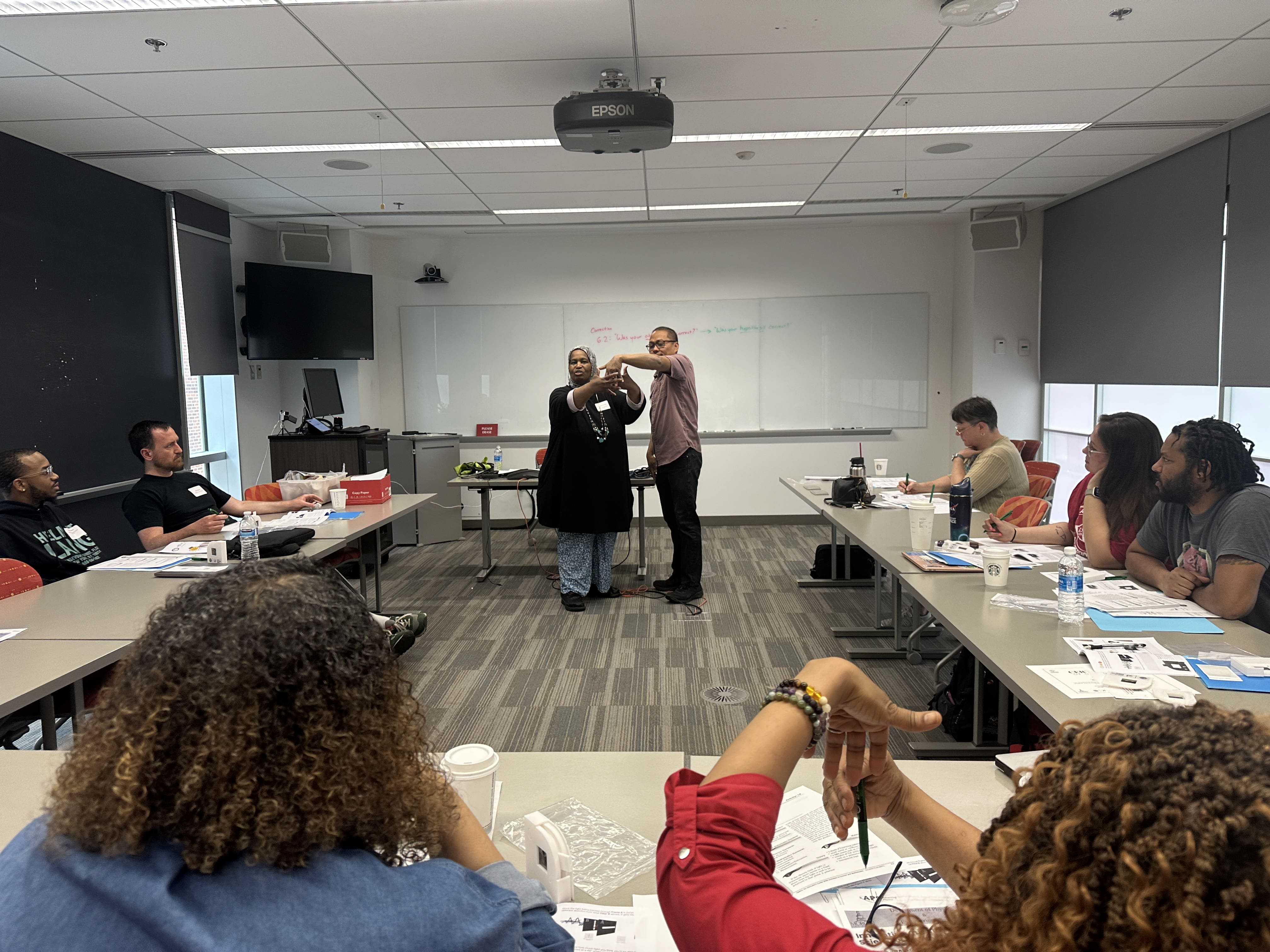 An instructor demonstrates a hands-on quantum activity to a group of teachers seated in a classroom during a professional development workshop.